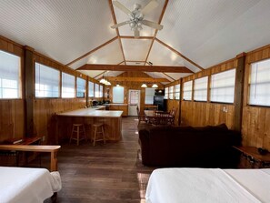 Interior de una cabaña con cocina, comedor y un gran techo de madera.