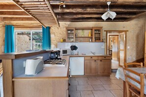 A compact kitchen with a gas stove, a microwave, and wooden cabinets.
