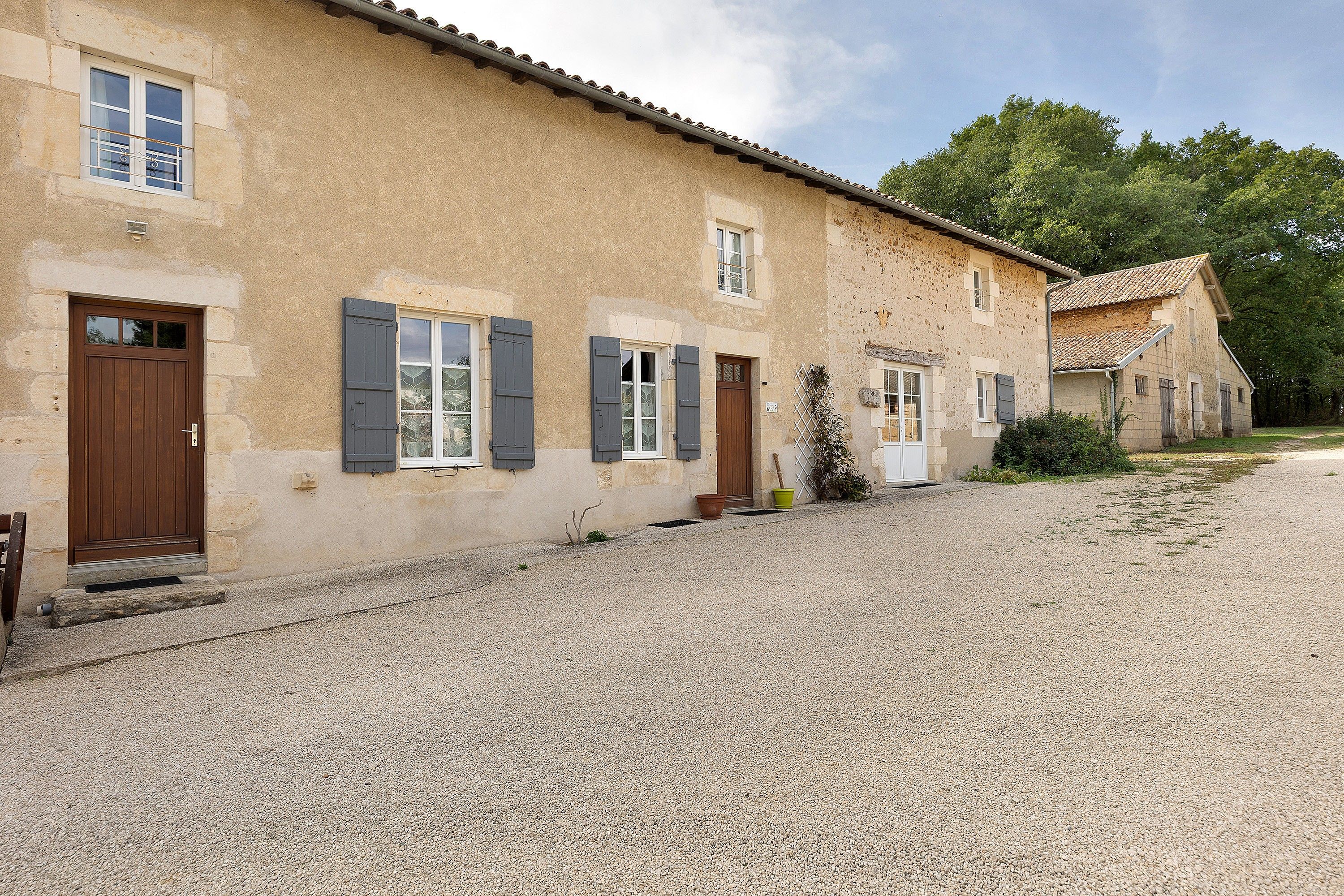 A two-story building with a gravel driveway, wooden doors, and shutters.