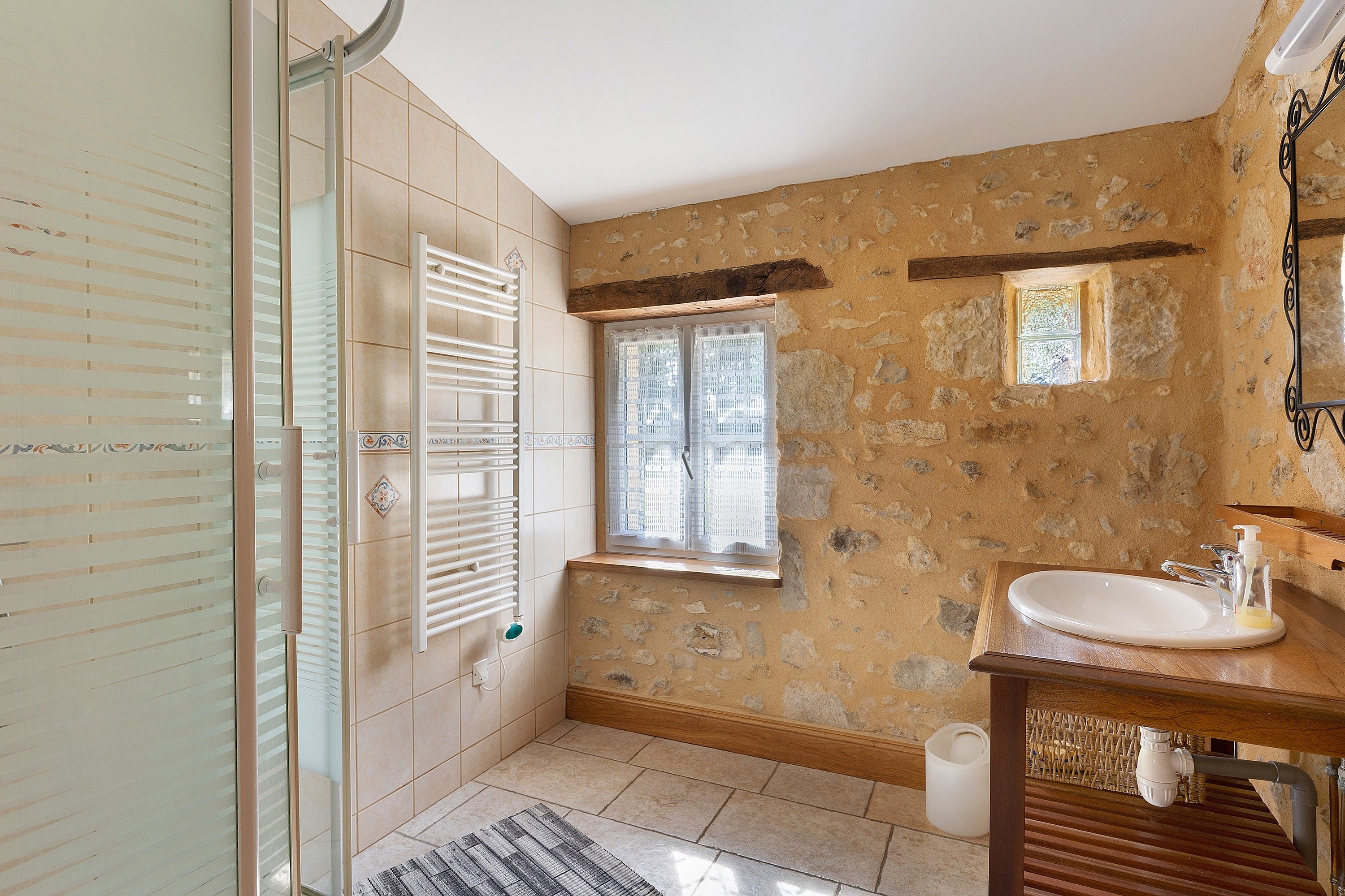 Une salle de bain avec une douche, un lavabo et une fenêtre.