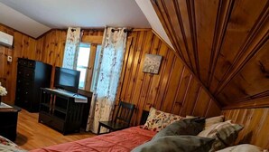 Une pièce confortable avec un lit, une commode, un téléviseur et une fenêtre avec des rideaux.