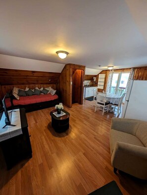 A cozy living room with a sofa, a coffee table, and a dining area with chairs and a table.