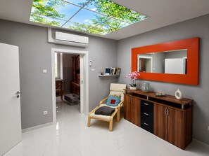 Un intérieur moderne agrémenté d’une verrière, d’un mur miroir, d’un meuble en bois et d’un espace salon.