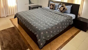 A bedroom with a bed, a ceiling fan, an air conditioning unit, a mirror, and curtains.