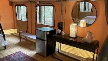 Une chambre de taille réduite comprenant un lit, un petit réfrigérateur, une machine à café, une lampe et un miroir.