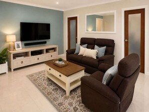 A living room with a flat-screen TV, a sofa, a coffee table, and a TV stand.