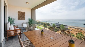 En balkon med et træbord, stole og krukker med planter.