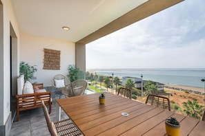 Ein Balkon mit einem Holztisch, Stühlen und Topfpflanzen.
