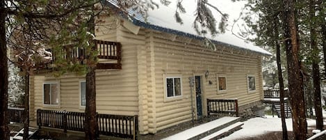 A log cabin with a front porch, a small window, and a door.