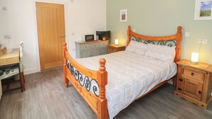 Une chambre à coucher avec un lit en bois, un bureau, une armoire et un téléviseur.