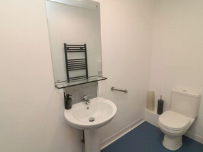 A bathroom with a white sink, a glass shelf, a towel rack, and a toilet. - Walcott Lodges - Barlings (Lincoln)