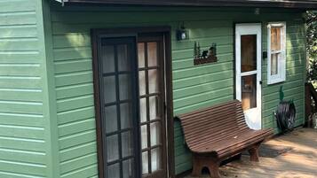 Una casa verde con una veranda in legno, una panchina e un'uscita.