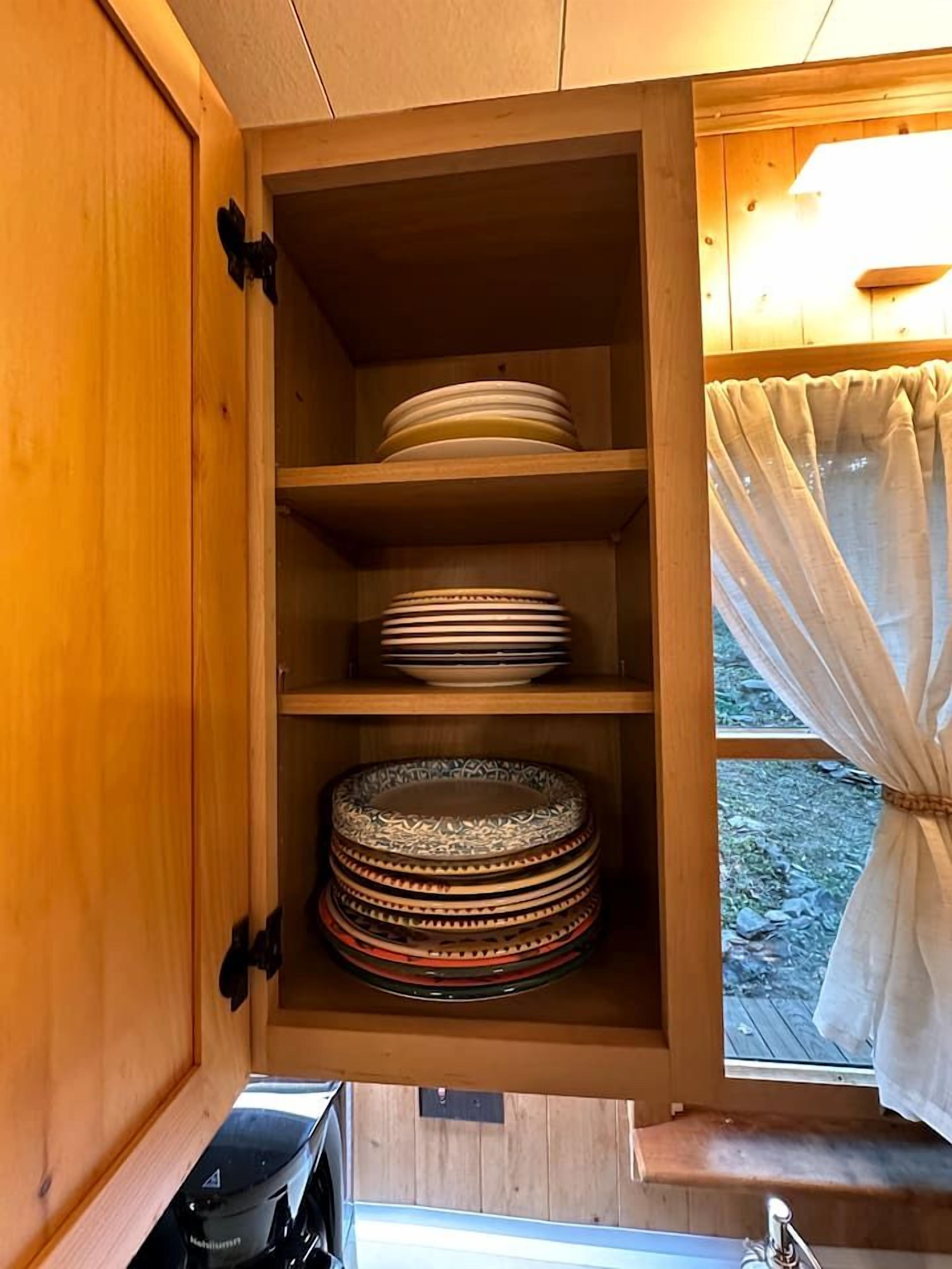 A wooden cabinet with shelves containing stacked plates.