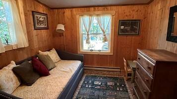 Una habitación acogedora con cama, cómoda y ventana con cortinas.