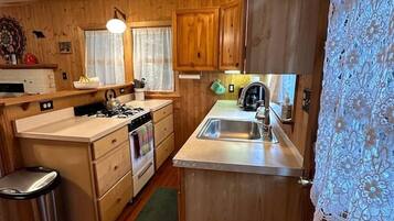 A compact kitchen with wooden cabinets, a sink, and a stove.