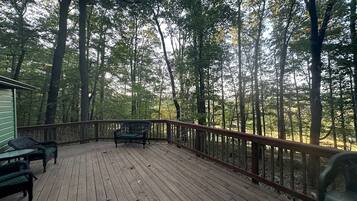 A wooden deck with a railing, surrounded by trees.