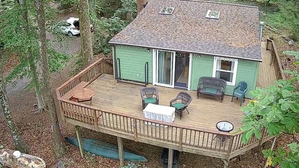 A cabin with a deck, outdoor seating, and a garage.