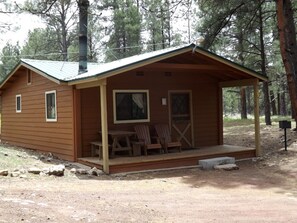 A small wooden cabin with a porch, two chairs, and a table. - Adorable Cabin with Indoor Jacuzzi in Arizona (Flagstaff)