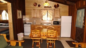 Une cuisine chaleureuse, aménagée dans un style rustique, avec des meubles en bois, une table à manger et des chaises, un réfrigérateur et un four à micro-ondes.