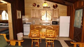 Une cuisine chaleureuse, aménagée dans un style rustique, avec des meubles en bois, une table à manger et des chaises, un réfrigérateur et un four à micro-ondes.