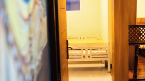 A hallway with a wooden floor leading to a room with a bed and a window. - Z Cafe and Apartment (Kathmandu)