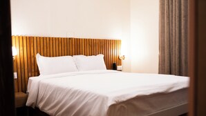A neatly made bed with white linens, a wooden headboard, and two bedside lamps. - Z Cafe and Apartment (Kathmandu)