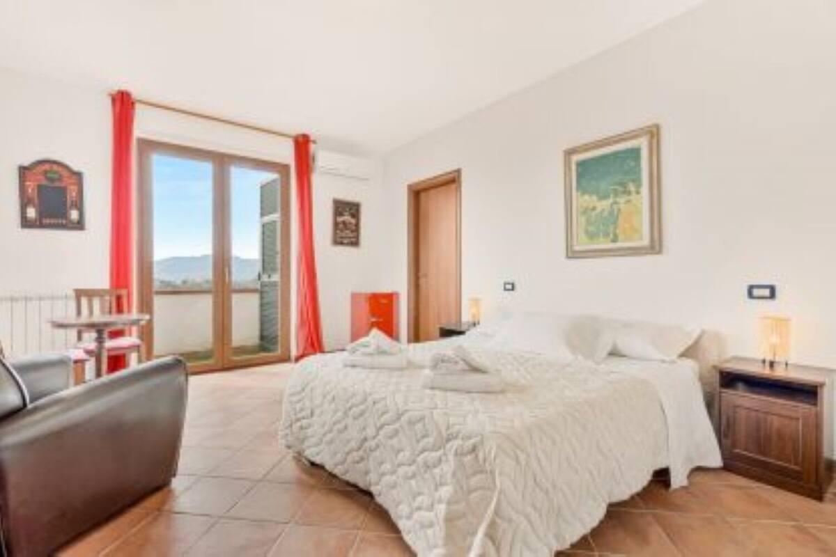 A bedroom with a bed, a nightstand, a chair, a window with a view, and a door.