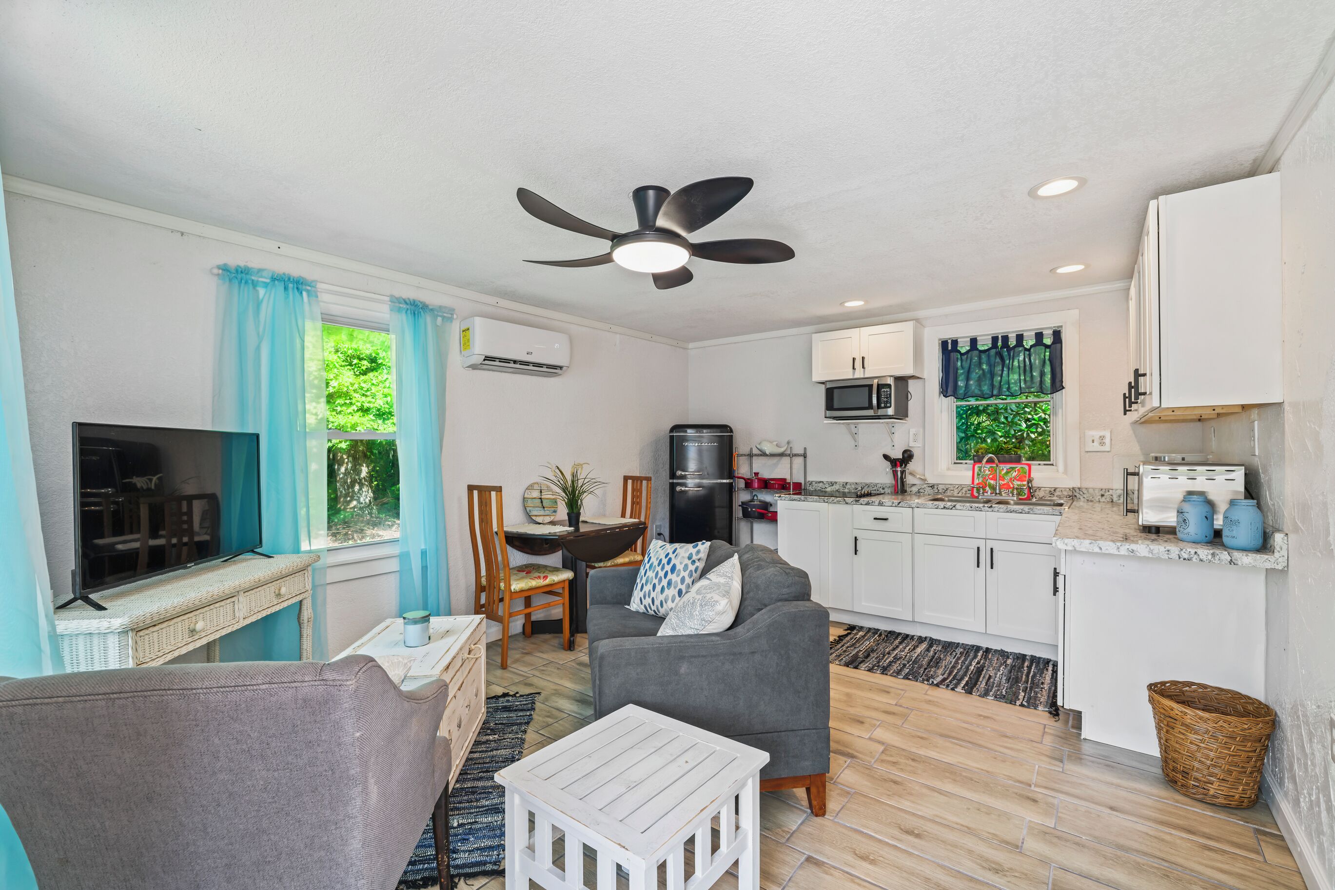 A compact living space with a kitchenette, a dining area, a seating area with a sofa, and a television.