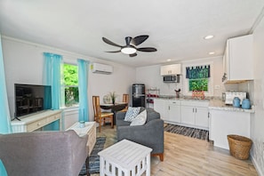 A compact living space with a kitchenette, a dining area, a seating area with a sofa, and a television.