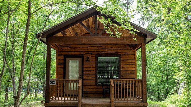Eine kleine Holzhütte mit Veranda, Tür und Fenster.