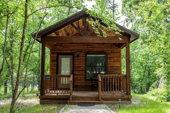 Eine kleine Holzhütte mit Veranda, Tür und Fenster.