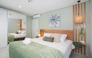 A bedroom with a large bed, a wooden headboard, a wall-mounted plant, and a ceiling fan. - Corporate Stays First Living (Asunción)