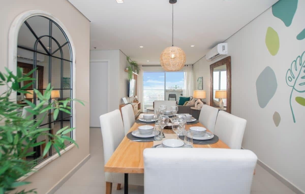 A dining area with a wooden table set for four, white chairs, and a hanging light fixture.