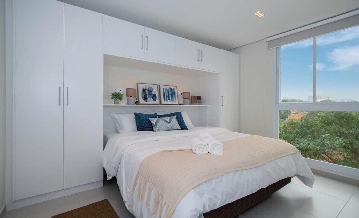 A bedroom with a bed, white wardrobe, and a window with a view.