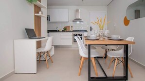 Una cocina moderna con armarios blancos, una estufa y un comedor con mesa y sillas.