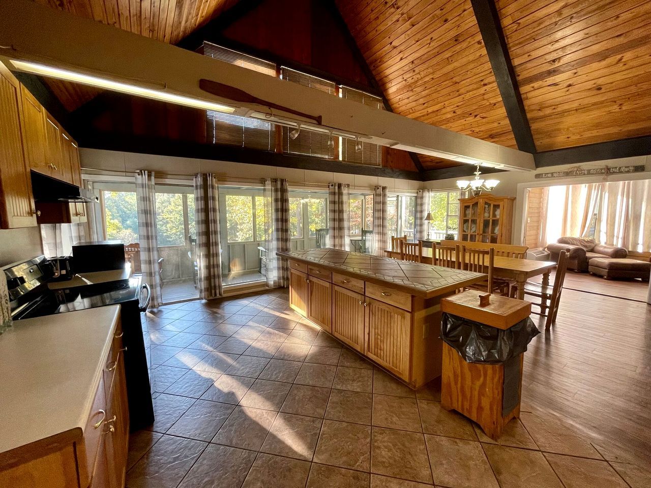 Una cocina amplia con una isla grande, armarios de madera y un comedor con mesa y sillas.