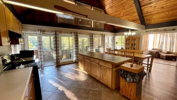 Una cocina amplia con una isla grande, armarios de madera y un comedor con mesa y sillas.