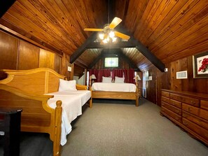 Ein Schlafzimmer mit zwei Holzbetten, einem Deckenventilator und einem großen Fenster.