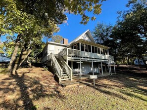 Une maison à deux étages avec un porche, un escalier et une petite table.