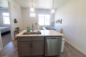 A kitchen with a dishwasher, a sink, and pendant lights. - Teal Waters - close to downtown! (Garden City)