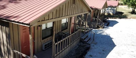 A building with a red roof, a porch with steps, and a gravel ground.