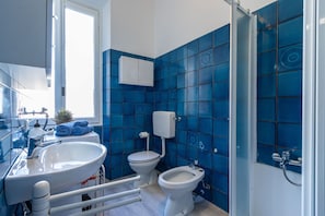 Un bany modern amb un rentapla, vàter, bidet i una finestra.
