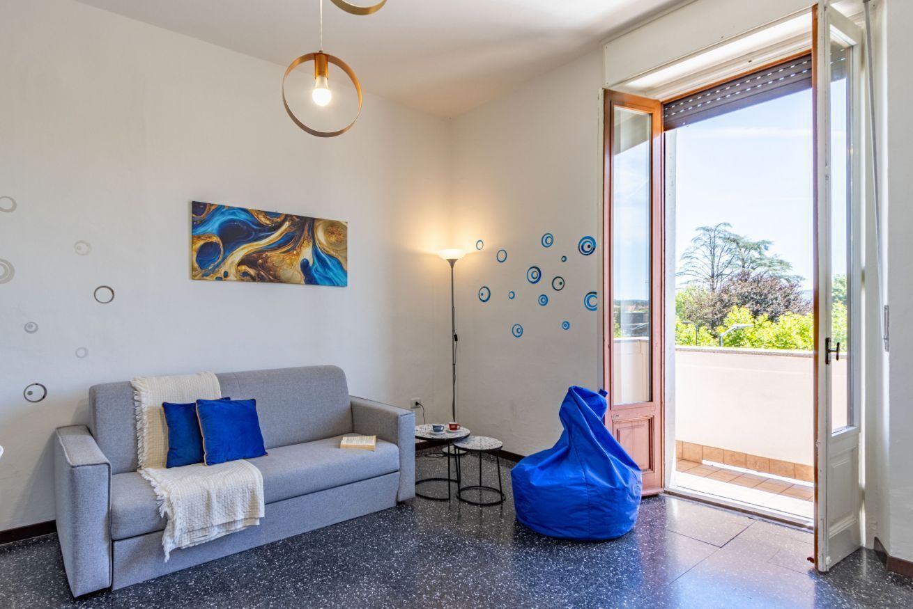 Un salon moderne avec un canapé, un fauteuil poire, un tableau et une lampe sur pied.