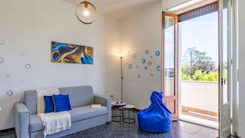 Un salon moderne avec un canapé, un fauteuil poire, un tableau et une lampe sur pied.