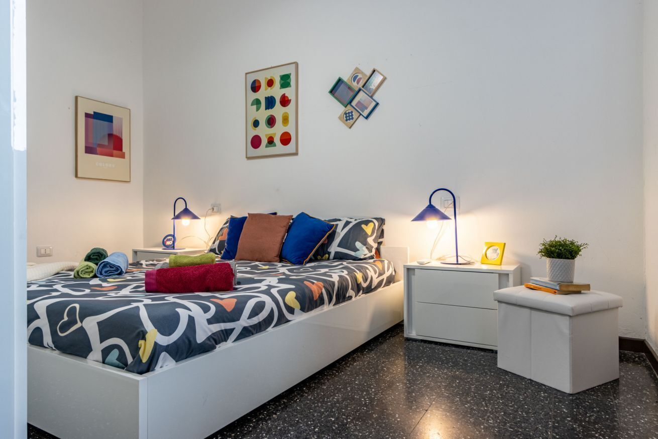 A modern bedroom with a bed, bedside tables, a nightstand, and wall art.