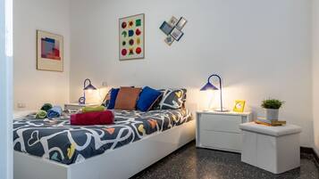 A modern bedroom with a bed, bedside tables, a nightstand, and wall art.
