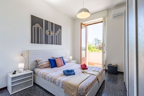 Ein Schlafzimmer mit Bett, Nachttischen, einer Stehlampe und Blick durch eine geöffnete Tür.