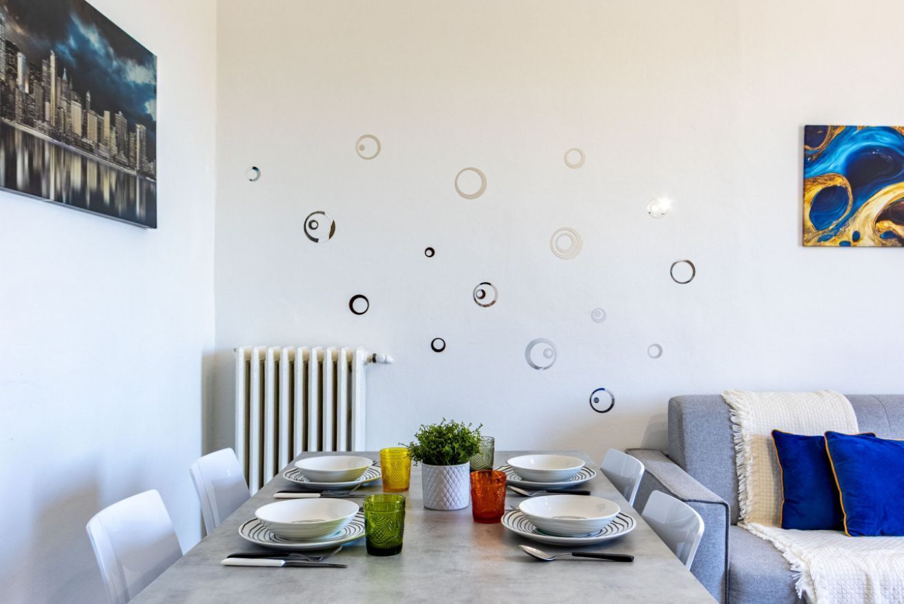A dining area with a table set for four, a radiator, and a sofa with cushions.