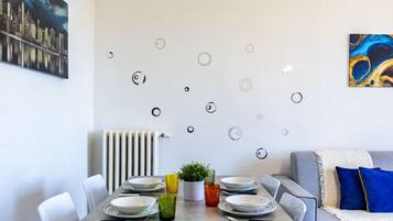 A dining area with a table set for four, a radiator, and a sofa with cushions.