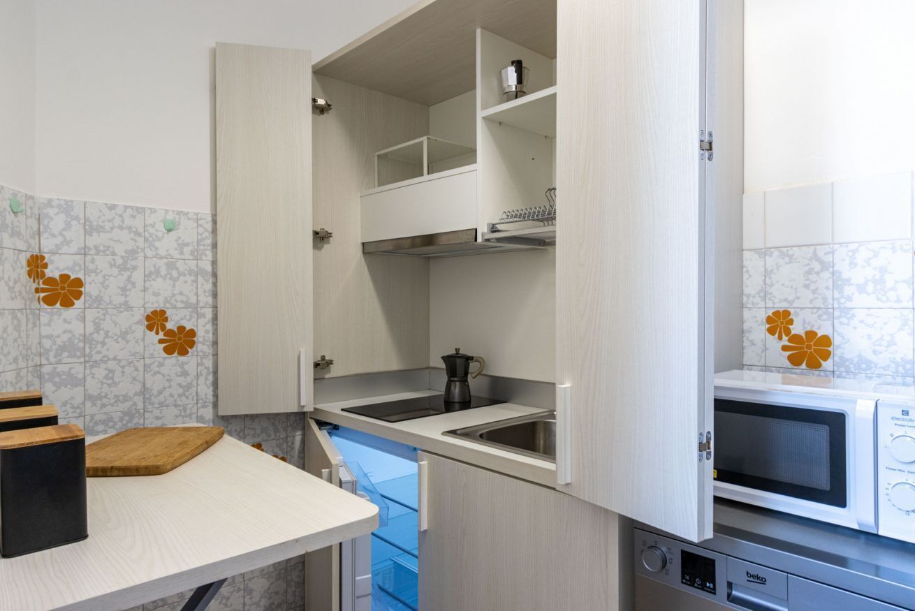 Una cucina compatta con forno a microonde integrato, macchina del caffè e lavello.
